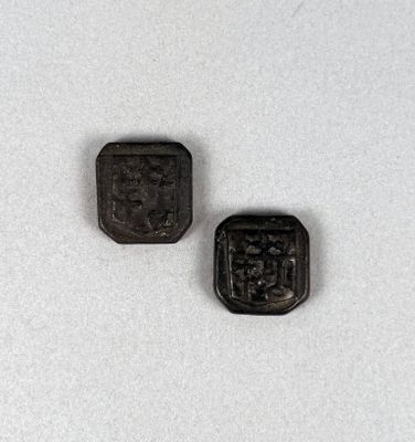 two small black buttons sitting next to each other on a white surface