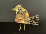 gold metal bird sculpture on black surface with black background