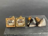 three pairs of gold and silver cufflinks sitting on top of a wooden block