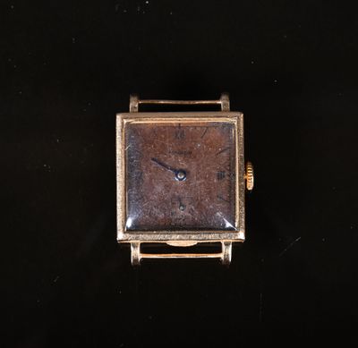 une petite montre carrée posée sur une surface noire