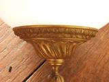 brass plated wall sconce with a white glass shade on it
