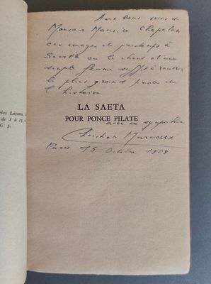 un livre ouvert, sur lequel repose une lettre manuscrite, posé sur une table