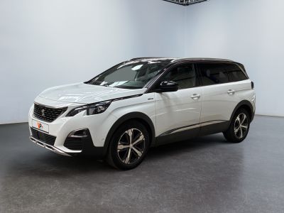 Une voiture blanche est garée dans une grande pièce équipée d'un ventilateur de plafond