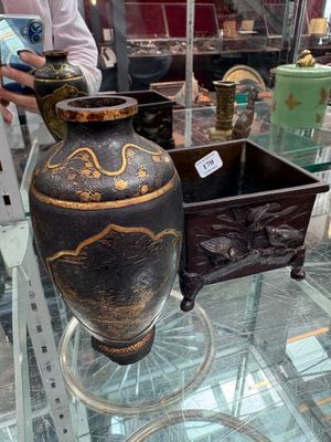 une table en verre sur laquelle se trouve un vase, avec un homme debout à côté