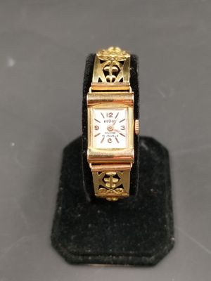 une montre en or posée sur un socle noir, sur une table