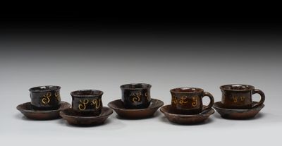 quatre tasses et soucoupes portant des chiffres, posées sur une table