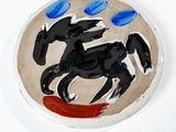 un cheval noir peint sur une assiette blanche à pois bleus