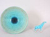 a small toy giraffe standing next to a blue bowl