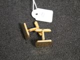 a pair of gold cufflinks with a price tag on them