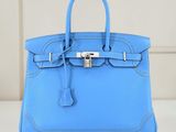 un sac à main en cuir bleu posé sur une table blanche