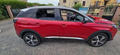 La voiture rouge est garée sur le bord de la route, dans le parking.