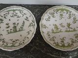 two plates with green and white designs on them sitting on a table
