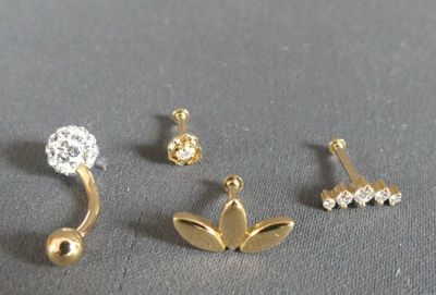 three pairs of ear piercings on a gray surface