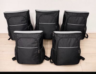 quatre sacs à dos noirs posés sur un plancher en bois