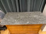 a marble top chest of drawers in the corner of a room