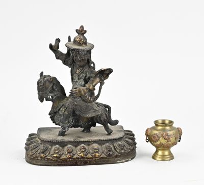 une statue représentant un homme à cheval, à côté d'un vase