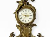 une horloge dorée ornée d'un oiseau sur fond blanc