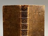 an old book sitting on top of a table next to a white wall