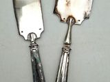 two silver spoons and a knife on a white surface
