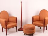 two orange chairs and a stool in a room with a white wall