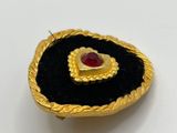 a close up of a gold and black broochle with a heart on it