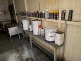 several buckets of paint sitting on a shelf in a garage
