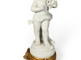 une figurine blanche représentant un garçon tenant un chien, posée sur un socle