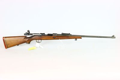 a rifle on a white surface with a white background