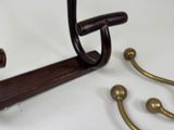 a wooden coat rack with a hook and a pair of brass hooks