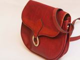a small red purse with a metal handle on a white surface