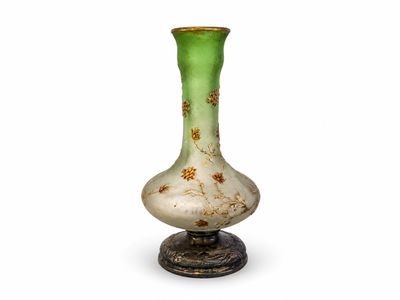 un vase vert et blanc posé sur un socle en métal