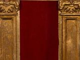 an ornate gold frame with a red velvet curtain in front of a white wall