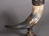 un objet en forme de corne posé sur un socle, sur une surface grise