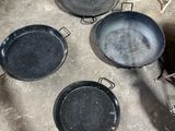 Plusieurs casseroles sont posées par terre à côté d'une cuisinière.