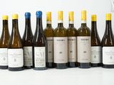 six bouteilles de vin sont alignées sur une surface blanche
