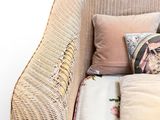a wicker chair with pillows and a pillow on top of it