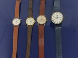 Quatre modèles de montres différents sont alignés sur un fond bleu