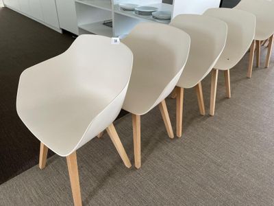 four white chairs are lined up in a row in a room