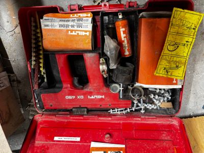 une boîte à outils rouge contenant des outils, posée par terre