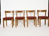 three wooden chairs with red upholstered cushions sit in front of a white backdrop
