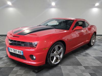 Une Chevrolet Camaro rouge est garée sur un sol à damier.