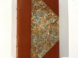 livre relié en cuir, orné de fleurs dorées et bleues sur fond blanc