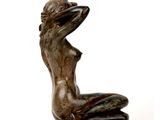 statue of a woman sitting on a rock with a hat on her head