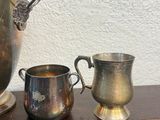 two silver cups and a silver ice bucket on a table