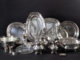 a lot of silver plates and bowls on the table