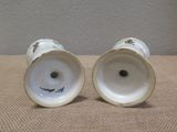 two white vases sitting on a table next to each other