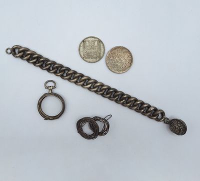 un gros plan sur un bracelet à maillons, une pièce de monnaie et une paire de boucles d'oreilles