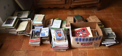 une boîte remplie de livres sur le sol, à côté d'une commode