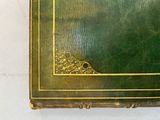 a green book with a gold border on top of it