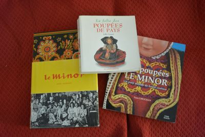three books on a bed with a red comforter and a red blanket